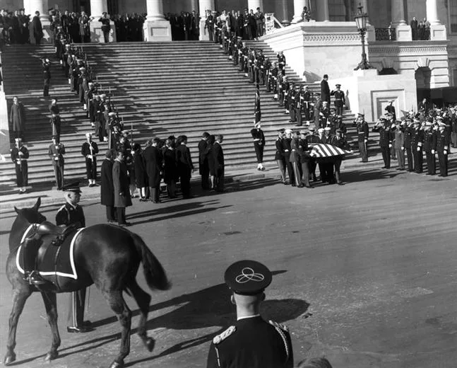 Flag-draped casket of President John F. Kennedy departs the East Front of the U.S. Capitol. The riderless horse Blackjack with empty reversed boots, a tradition with roots in the Roman republic, is seen in lower left. Public domain, Wikimedia Commons.