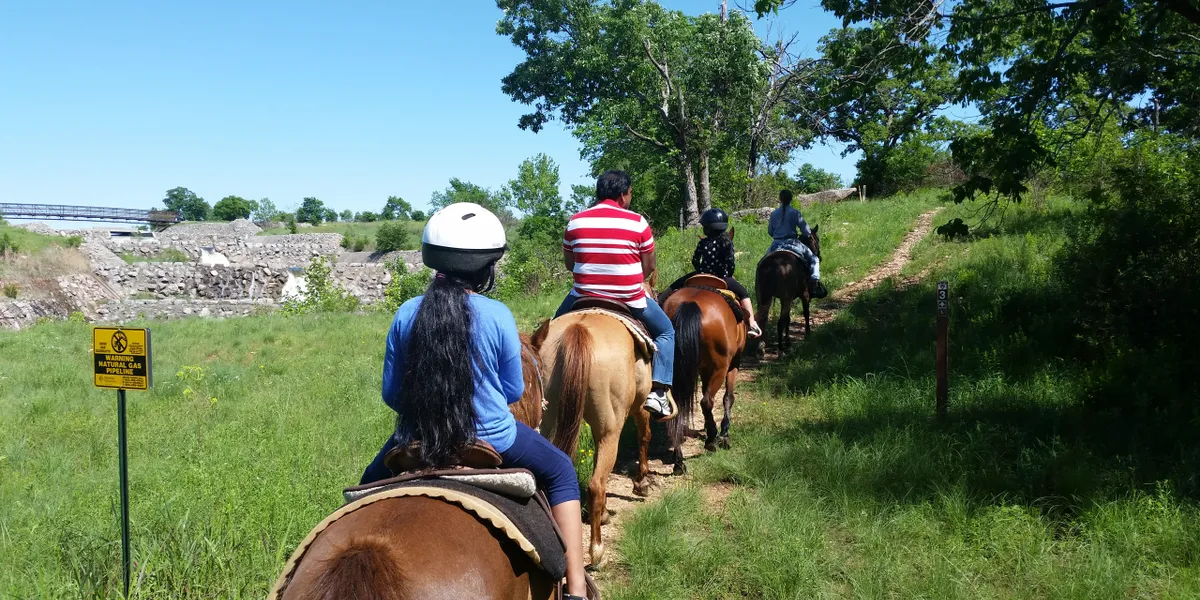Riders follow a grassy trail in single file.
